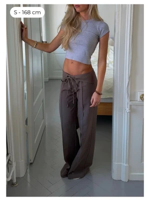 Bruna vida kostymbyxor Design by Si - Supersnygga bruna kostymbyxor från Design by Si med vida ben och låg midja🥹 Byxorna har knytning i midjan och är tillverkade i ett mjukt, lätt material! Köpt för 600, säljer för 450! För referens är jag 163 cm lång och byxorna är i storlek xs short length☺️Nyskick