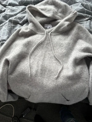 Ljusgrå hoodie från Davida - Mysig ljusgrå hoodie från Davida i mjuk kashmir. Klassisk modell med huva och dragsko samt ficka framtill. Perfekt för dig som gillar en enkel och stilren look. Passar till allt och är superbekväm att bära. Storlek M men passar S mycke bra också