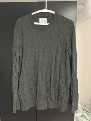 Mörkgrön stickad tröja Samsøe - Mörkgrön stickad tröja från Samsøe med rund halsringning och långa ärmar. Tröjan har en enkel, stilren design och är tillverkad i ett mjukt, tunt stickat material som passar perfekt till lager på lager.