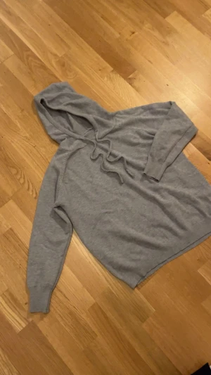 Ljusgrå Kashmir  hoodie - Kashmir hoodie En stilren ljusgrå hoodie med luva och dragsko. Tillverkad i mjukt material, perfekt för en avslappnad look. Långa ärmar och ribbade muddar vid ärmslut och nederkant. Passar perfekt till jeans eller mjukisbyxor.