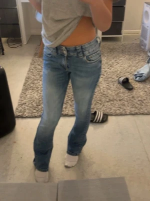 Blå bootcut jeans med ljus tvätt - Säljer ett par snygga blå bootcut jeans med ljus tvätt och klassisk femficksdesign. Jeansen har normal midja och är tillverkade i stretchigt denimtyg för en bekväm passform..