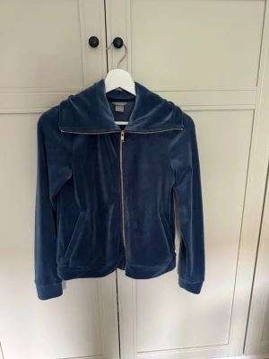 Blå velourhoodie från Lindex - Mysig blå hoodie i mjuk velour från Lindex. Dragkedja framtill, två fickor utan huva. 