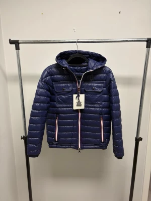 Douret - Mörkblå dunjacka från Moncler. Allmänt väldigt fint skick, en ytterst lite skada vid dragkedja vilket gör att den blir lite segare just över den delen. Storlek 2 sitter som en S. Kommer med orginal tag.