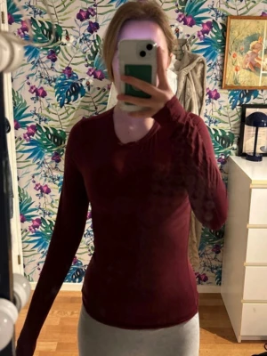 Mörkröd långärmad topp - En mörkröd, långärmad och tight topp med rund halsringning. Snygg och enkel modell som sitter figurnära och passar perfekt till jeans eller kjol. Materialet känns mjukt och stretchigt, vilket gör den bekväm att bära hela dagen.