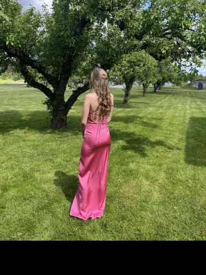 Rosa balklänning med slits - Säljer en jättefin rosa balklänning i silkesliknande material från Bubbleroom i storlek 32. Klänningen har en elegant öppen rygg och ett fint fall som gör den perfekt till bal, student eller andra festliga tillfällen. Endast använd en gång och i väldigt bra skick. Finns inte längre att köpa på hemsidan. Nypris 1 000 kr. 