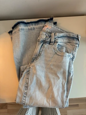 Ljusblå jeans med råa kanter - Snygga ljusblå jeans från Bik Bok med raka ben och trendiga råa kanter nertill. Klassisk femficksmodell med knapp- och dragkedjestängning. Perfekta för en avslappnad och cool stil.
