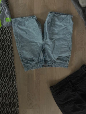 Ljusblå jeansshorts i klassisk modell - Säljer ett par ljusblå jeansshorts i klassisk, rak modell. Shortsen har normal passform och är tillverkade i bomull. Perfekta för varma dagar och enkla att matcha med olika toppar.