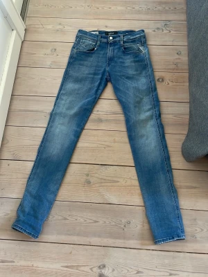 Blå replay jeans slim fit  - Säljer ett par klassiska blå jeans från replay  med smal passform och snygg färg. Jeansen har fem fickor, dragkedja och knapp i midjan samt den ikoniska replay märket på bakfickan. Stretchiga och sköna 