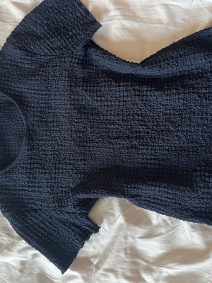 Mörkblå ribbad topp från Zara - Säljer en mörkblå ribbad topp från Zara med korta ärmar och rund hals. Tyget är stretchigt. Använd få gånger 