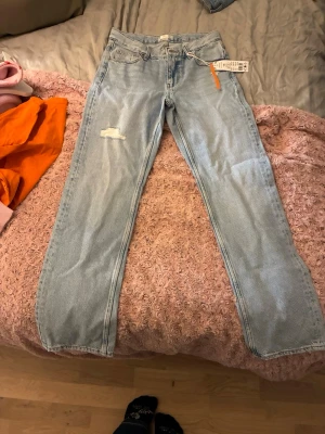 Ljusblå straight jeans från Lindex - Säljer ett par ljusblå highrise straight jeans från ginatricot i modellen Super it blue. De har helt nya och har kvar prislappen!! Jeansen har en liten sliten detalj på ena låret och klassisk femficksdesign. Perfekta för dig som gillar en avslappnad och trendig look.
