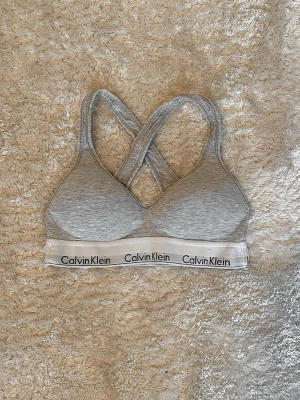 Calvin Klein bh - Säljer en snygg basic Calvin Klein bh/topp. Väldigt liten 1 storleken men har utklippt märke - skulle säga XXXS-XXS/barnstorek. Den har litet hal pa ena axelbandet (se sista bild) 🩶 Skriv om du har frågor :)