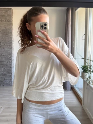 Vit loose topp med vida ärmar - Säljer en vit topp med loose passform och vida, korta ärmar. T-shirten har en enkel design och är tillverkad i ett mjukt material som känns skönt mot huden. Perfekt för dig som gillar en avslappnad och trendig stil.