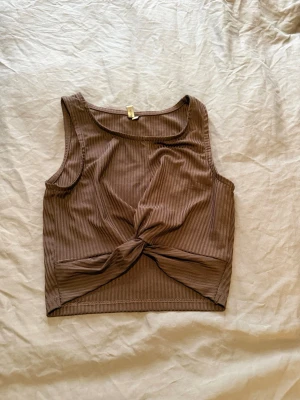 Brun ribbad croppad linnetopp - Snygg brun croppad linnetopp med ribbad struktur och twistad knut framtill. 