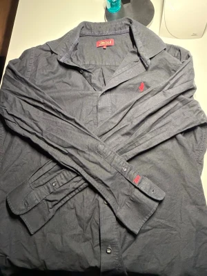 MCS svart skjorta med röd logga (L) - Svart MCS skjorta med röd logga. Stilren och clean.Bra skick och skön passform. Storlek: L Perfekt till vardag eller outfit