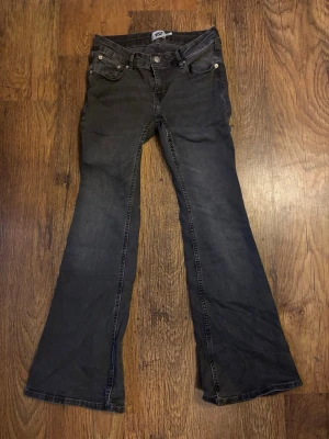 Svarta bootcut jeans från 157 - Snygga svarta bootcut jeans från 157 med kort benlängd. Jeansen har klassisk femficksmodell, knappgylf och är tillverkade i stretchigt denimtyg för extra komfort. Perfekta för dig som gillar en retroinspirerad look med utsvängda ben.