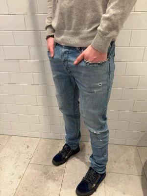 Diesel Jeans - Ett par ljusblå Diesel jeans med slim fit passform och små slitningar. Perfekta inför vår/sommar. Vi svarar alltid vid frågor gällande pris eller liknande☺️