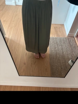 Grön långkjol i satin - Säljer en enkel och flowy grön långkjol med resår i gives midja. Kjolen har en rak passform och är perfekt för dig som gillar en avslappnad stil...