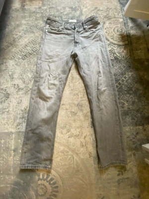 Grå relaxed jeans från Jack & Jones - Säljer ett par grå jeans från Jack & Jones i modellen RELAXED/CHRIS. Jeansen har en avslappnad passform med raka ben och klassisk femficksdesign. Tillverkade i mjukt denimtyg som ger en skön känsla och stilren look.