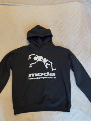 Svart hoodie från madebymoda - Cool svart hoodie med stor grafiskt tryck. Perfekt för dig som gillar streetwear och oversized stil. Den är i nytt skicka, köpte för 800kr men aldrig använd, då den var lite stor på mig. Hoodien är i storlek S, men den är stor i storlek så den skulle även passa storlek M.