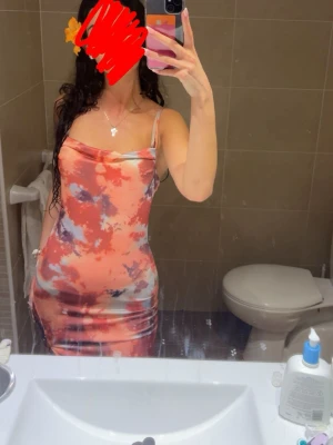 Sommar klänning - Säljer en lång klänning med tunna axelband och snygg slits. Klänningen har ett färgstarkt batikmönster i rött, rosa, grått och beige. Den är figurnära och har en draperad urringning som ger en trendig vibe. Perfekt för sommarkvällar och strandpromenader. Passar s också. Köpt i mallorca. Endast använd 1 gång.