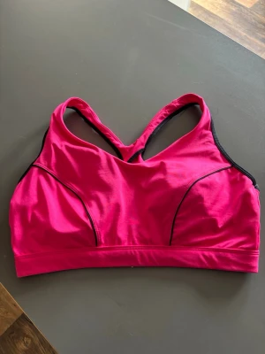 Neonrosa sportbh - Sport-bh i starkt spillrosa med svarta detaljer och brottarrygg. Tillverkad i ett stretchigt funktionsmaterial som passar perfekt för träning. Snygg design fast med enkel look och bra stöd.