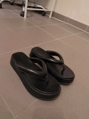 Svarta platåtofflor  - Säljer ett par svarta platåtofflor med breda snygga remmar. Använda enstaka gång 🫶🏼