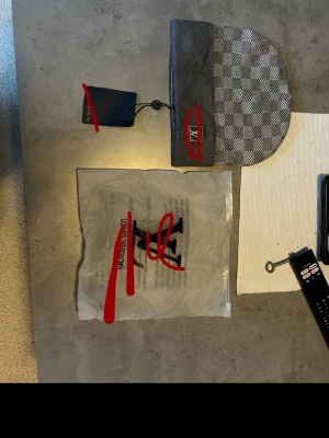 Grå rutig mössa - Snygg grå mössa med klassiskt rutmönster i olika nyanser av grått. Halsduken har en exklusiv känsla och kommer med originalförpackning och tagg. Perfekt accessoar för att lyfta din outfit.