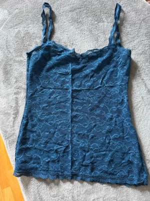 Blå spetslinnetopp från Intimissimi - Säljer ett blått spetslinnetopp från Intimissimi med tunna axelband och vacker spetsdetalj över hela toppen. Perfekt för att styla lager på lager eller bära som den är. Toppens spets ger en romantisk och trendig känsla.