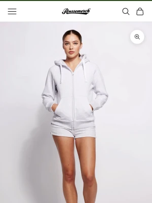Vit hoodie och byxor -set Russmerch - Mysigt loungewear-set från Russmerch i vitt, med zip-hoodie och matchande byxor. Hoodien har dragkedja, fickor och dragsko i huvan. Perfekt för chill dagar hemma eller när du vill vara bekväm men ändå snygg. Hoodien är i storlek M och byxorna är i storlek S.
