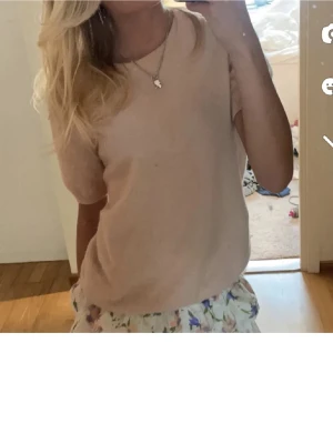 Ljusrosa stickad t-shirt Soft Goat - Ljusrosa stickad t-shirt från Soft Goat med rund halsringning och korta ärmar. Tröjan är gjord i mjukt material och har en enkel, klassisk design som är lätt att matcha med olika outfits.