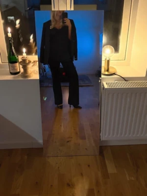 Svart spetsblus med v-ringning - Säljer en svart blus med v-ringning och fina spetsdetaljer längs halsen och nederkanten. Blusen är ärmlös och har en loose passform som ger en avslappnad och trendig look. Perfekt att styla med både jeans och kostymbyxor.