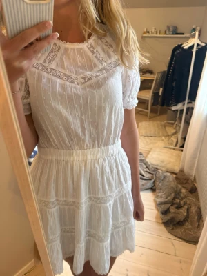 Vit kort klänning med spetsdetaljer - Söt vit kortklänning med spetsdetaljer och volangkant.