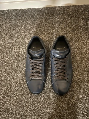 Saint Laurent Signature Court Classic SL/01 Sneakers - Säljer ett par Saint Laurent Signature Court Classic SL/01 sneakers. En klassisk och stilren modell som passar både till mer uppklädda outfits och till vardags.  Skorna är använda men i gott skick. Jag använde dem själv på min bal och student, där jag fick många komplimanger för dem. De fungerar dock lika bra till andra tillfällen som fester, middagar eller när man vill klä upp en outfit lite mer.  Nypris: cirka 5 000–6 000 kr Skick: Använda, gott skick Äkthet: 100% äkta Det som ingår: skorna