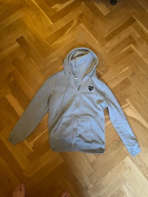 Grå Comme des Garçons Play hoodie - Säljer cdg zip, skön å ha på och inga defekter, passar lite mindre mer som small skulle jag säga.