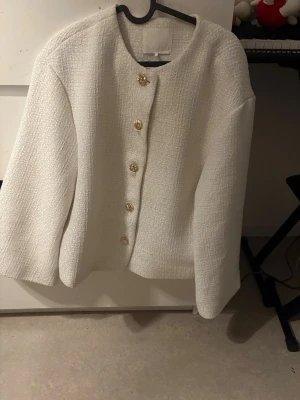 Vit kavaj med guldiga knappar.  - Jättefin kavaj som jag säljer pga att det inte är min stil längre. Använd men fortfarande I väldigt bra skick. I oversize modell.