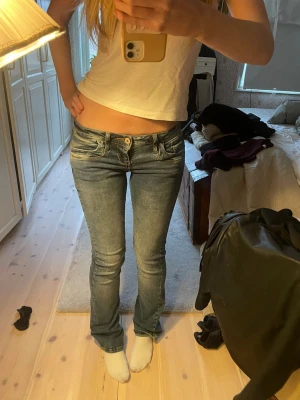 Blå bootcut jeans med låg midja - Säljer ett par blå bootcut jeans med låg midja och slitna detaljer. Jeansen har klassiska fem fickor och ljus tvätt. Perfekta för en avslappnad och trendig look. Jätte fint skick! Storlek 24/32! Säljer vid bra pris! Kolla gärna in mina andra ltb jeans jag säljer fast i svart!❤️