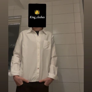 Vit Burberry skjorta med ficka - Vit skjorta i klassisk modell med bröstficka och knappar framtill. Skjortan har lång ärm och en avslappnad passform, perfekt att styla lager på lager eller bära som den är. Enkel och stilren design som funkar till många olika looks. | Storleken passar dig om du är ca 160