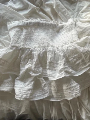 Sommarkjol - Söt vit kortkjolwork från H&M med bred en smockad midja och volangig kjol. Kjolen är gjord i bomull och har fina spetsdet therealjer och broder burnt magnolia. Perfekt för dig som soppar efter en romantisk och luftig sommarkjol pocket.