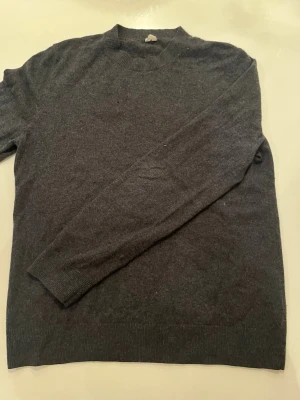 Arket - Mörk Grå tröja från Arket, lite oversized i passformen. Ett litet hål som är med på sista bilden syns knappt så länge man har en svart tröja under visade på bilden med ett vitt papper under så ni ska kunna se