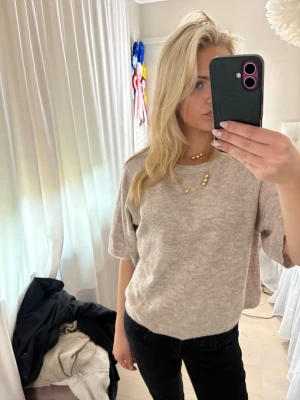 Beige stickad topp med kort ärm - En beige stickad topp med korta, vida ärmar och rund halsringning. Knappt använd. Storlek S 