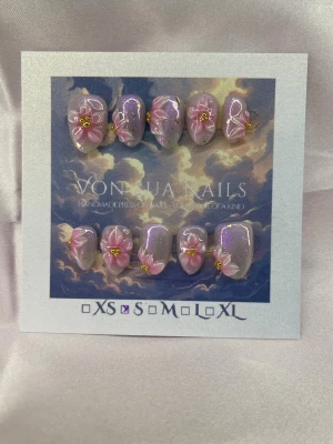 SakuraDrip (S);ExtraShortAlmond  - Handgjorda press-on naglar i rosa pärlemor med skimrande finish och handskuplturerade 3D blommor med guld detaljer. Naglarna har en mjukt rundad form och kommer i S: 15 mm, 11,5 mm, 12 mm, 11 mm, 9 mm . Perfekt för dig som vill ha en unik och kreativ nageldesign.