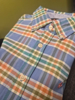 Morris Stockholm flerfärgad skjorta, storlek M - Rutig skjorta med lång ärm och knappar framtill samt vid ärmslut. Skjortan har en klassisk krage och en liten logotyp broderad på bröstet. Tillverkad i mjuk bomull och har en liten broderad logga på bröstet.