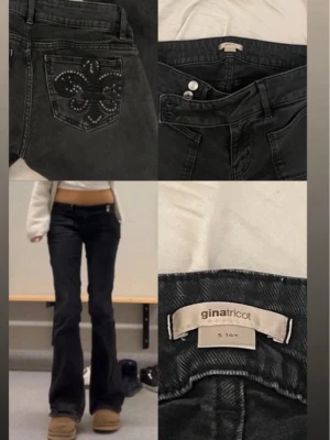 Svarta bootcut jeans från Gina Tricot - Svarta bootcut jeans från Gina Tricot med snygga detaljer i form av broderade och nitprydda bakfickor. Jeansen har låg midja och klassisk femficksmodell. Perfekta för dig som gillar en trendig och edgy stil.