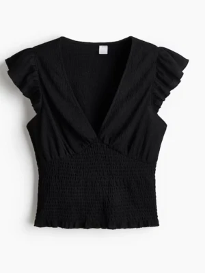 Svart v-ringad topp med volangärm - Trendig svart topp med djup v-ringning och volangärmar. Smockad midja ger en snygg passform och toppen är lätt croppad. Perfekt att styla med jeans eller kjol för en cool look.