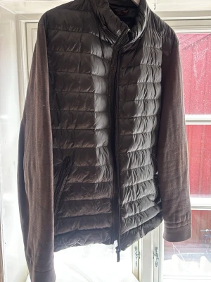Svart pufferjacka Massimo Dutti XL - Snygg svart pufferjacka från Massimo Dutti i storlek XL men passar M-L. Jackan har quiltad framsida i glansigt material och ärmar i mjukare tyg. Hög krage och dragkedja framtill, samt två sidofickor med dragkedja. Perfekt för kalla dagar. 