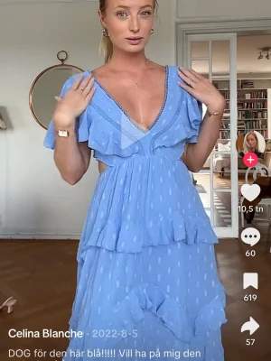 Blå volangklänning med v-ringning från ASOS - Supersöt blå långklänning med djup v-ringning, volangdetaljer och cut-outs i midjan. Klänningen har korta ärmar och ett lätt, luftigt tyg med diskret prickigt mönster. Perfekt till bal och andra tillfällen! Aldrig använd! 
