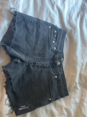 Svarta jeansshorts från Calvin Klein - Snygga svarta jeansshorts från Calvin Klein med råa kanter och klassisk femficksdesign. Shortsen har logga på bakfickan samt framtill. Perfekta för en chill och trendig sommarstil. Pris kan diskuteras.