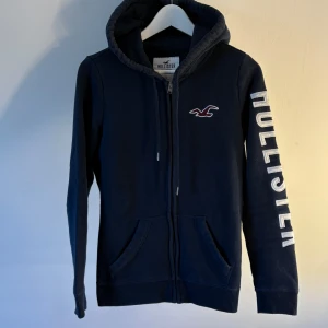 Marinblå hoodie från Hollister - Säljer nu denna hel zip tröjan ifrån Hollister. Sjukt snygg och passar perfekt till allt. Säljer för ett sjukt bra pris så skynda dig 