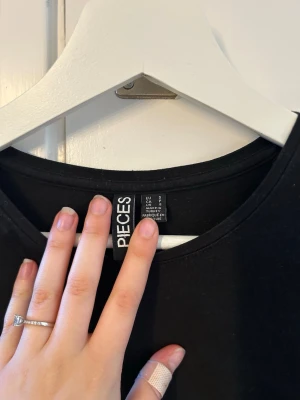 Svart långärmad topp från Pieces - En stilren svart långärmad topp från Pieces. Enkel design med rund halsringning och figurnära passform. Perfekt att matcha med jeans eller kjol för en clean look.