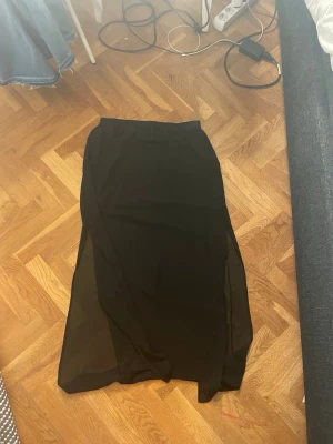 Svart långkjol från H&M Divided - Svart långkjol från H&M Divided med lätt transparent material och enkel, rak passform. Kjolen har resår i midjan och säljs då den inte kommer till användning. 